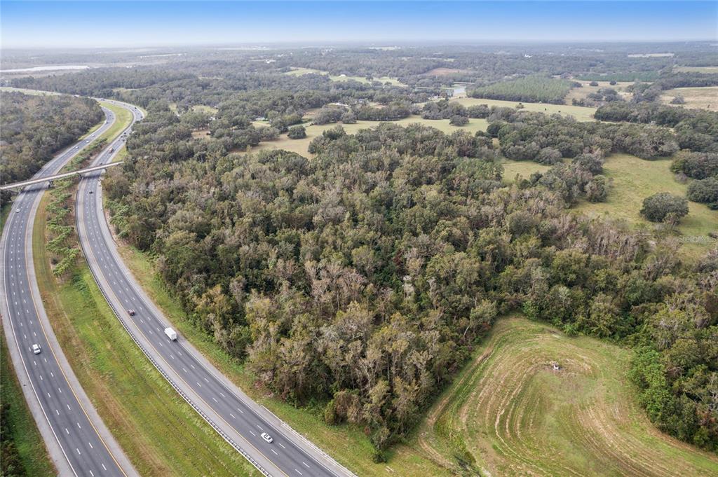 An aerial view shows a wooded lot adjacent to a multi-lane highway — 0 CHURCH ROAD, BROOKSVILLE, FL