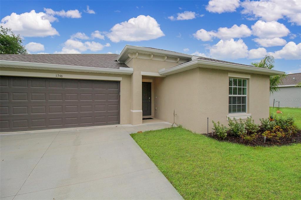 A single-story house with a beige stucco exterior, a brown garage door, and a front lawn — 1346 FIRESIDE STREET, PORT CHARLOTTE, FL