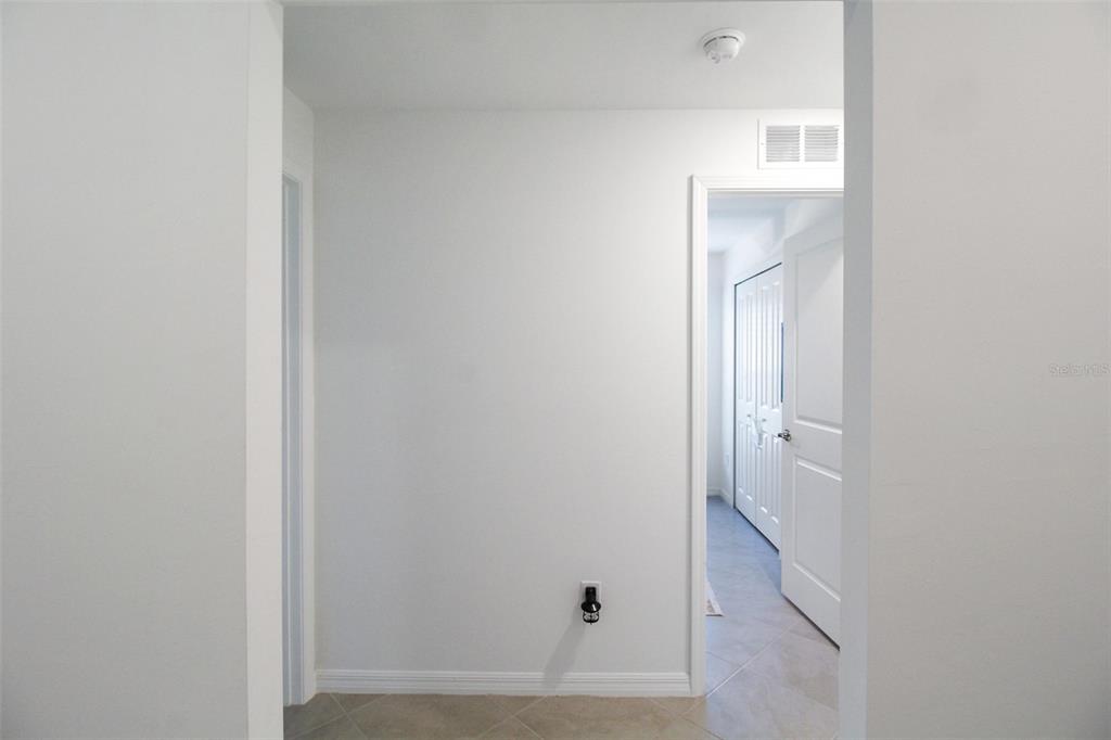 A white hallway features tiled flooring, a wall outlet, and a doorway leading to a closet — 1346 FIRESIDE STREET, PORT CHARLOTTE, FL