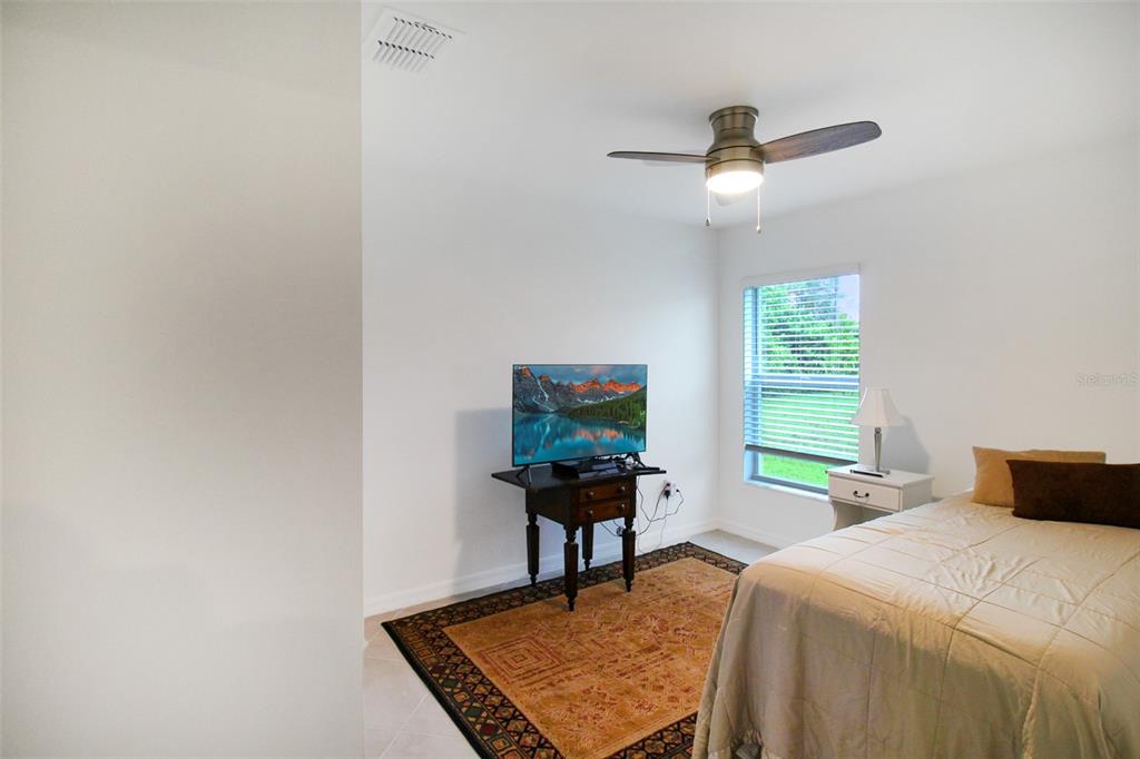 A bedroom features a ceiling fan, a television on a small table, and a bed — 1346 FIRESIDE STREET, PORT CHARLOTTE, FL