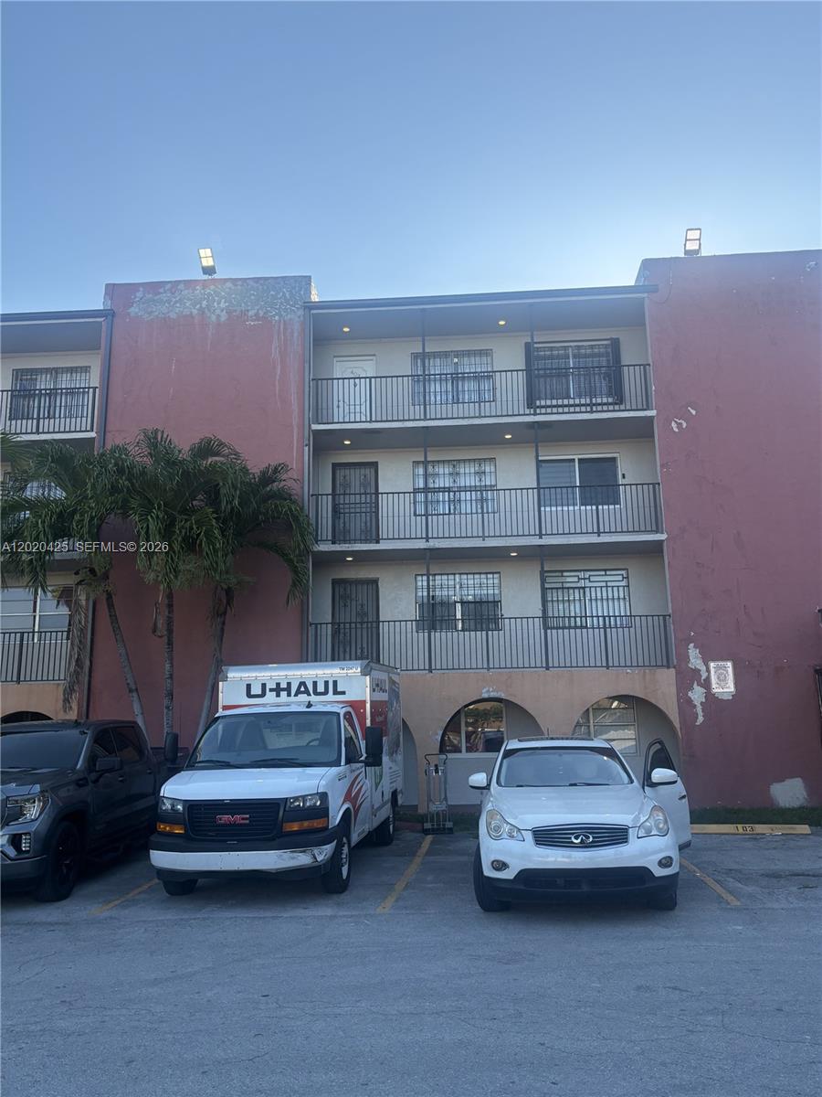 A three-story pink apartment building features exterior balconies and a parking lot in front — 6620 W 2nd Ct # 403, Hialeah FL 33012, HIALEAH, FL