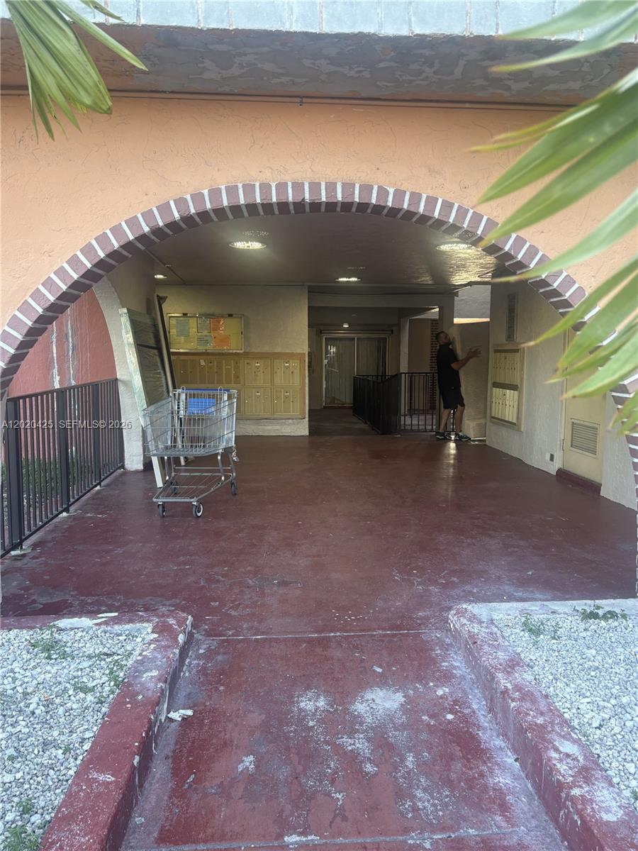 An outdoor covered entryway features a brick-accented archway, mailboxes, and a shopping cart — 6620 W 2nd Ct # 403, Hialeah FL 33012, HIALEAH, FL