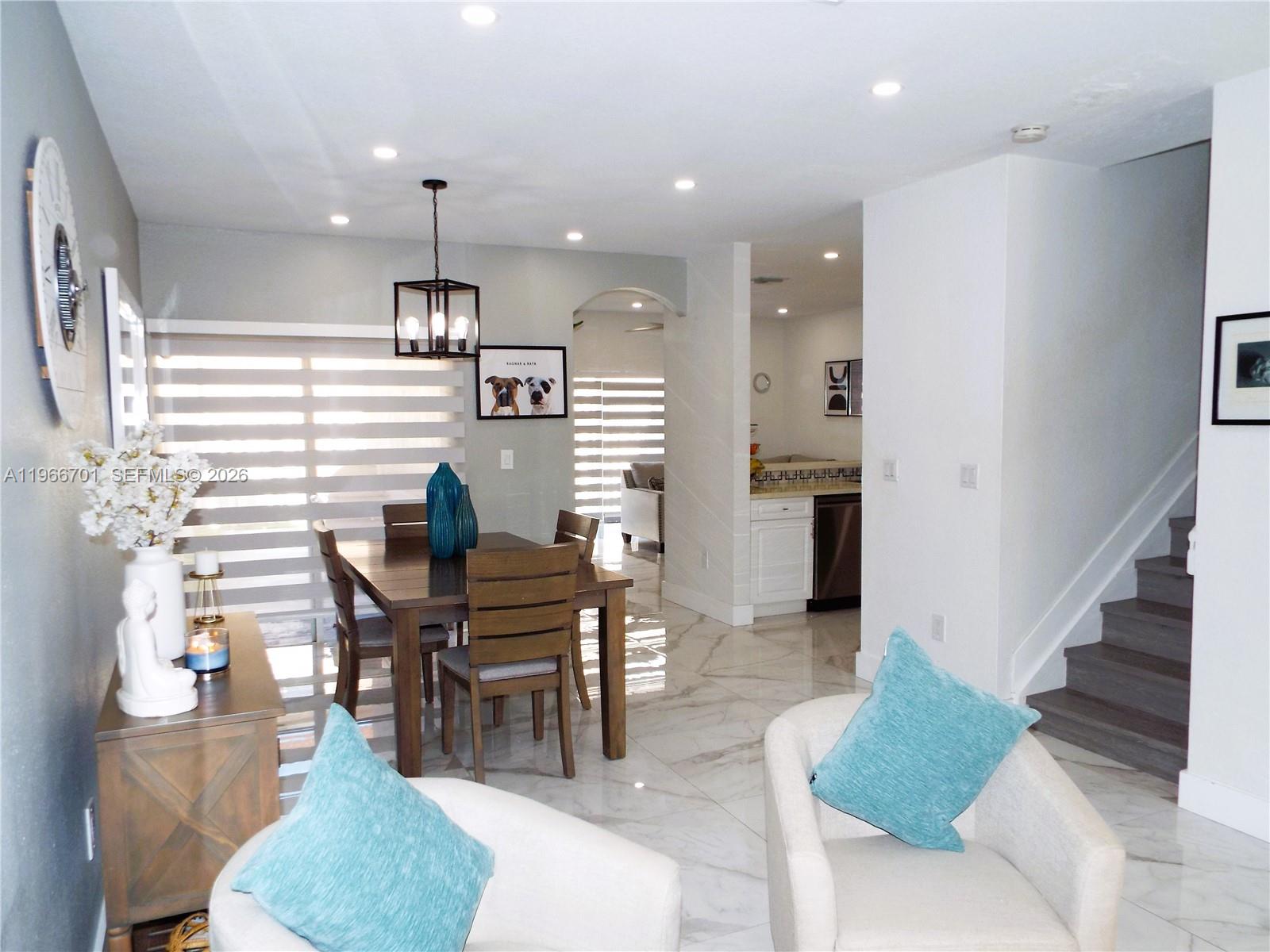 A dining area with a wooden table and chairs sits near a kitchen and stairs — 21470 SW 85th Path, Cutler Bay FL 33189, CUTLER BAY, FL