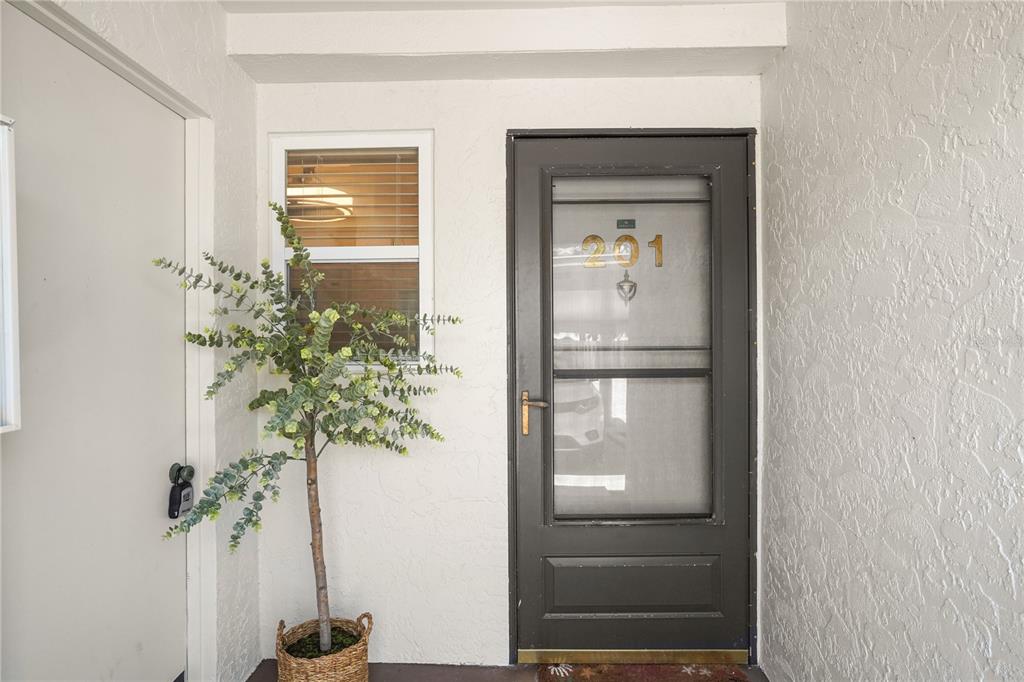 A gray front door with the number 201 and a potted plant sit in an entryway — 5673 MIDNIGHT PASS ROAD UNIT 201, SARASOTA, FL