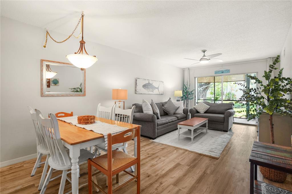 A living and dining room with wood-look flooring, a gray sofa set, and a dining table — 5673 MIDNIGHT PASS ROAD UNIT 201, SARASOTA, FL
