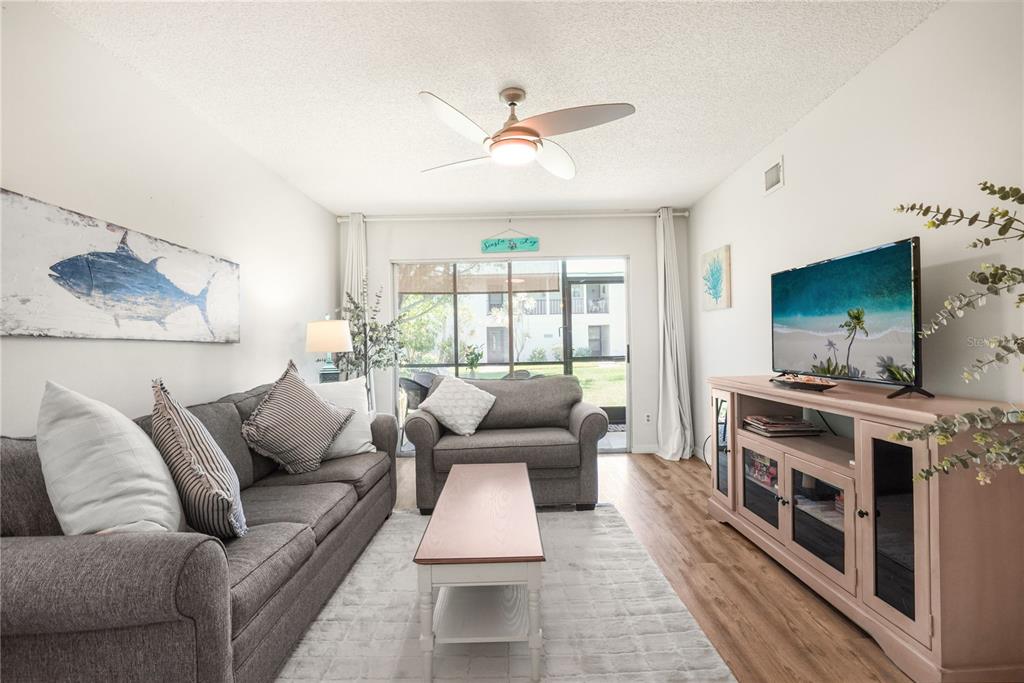 A living room features a gray sofa, a loveseat, a coffee table, and a television — 5673 MIDNIGHT PASS ROAD UNIT 201, SARASOTA, FL