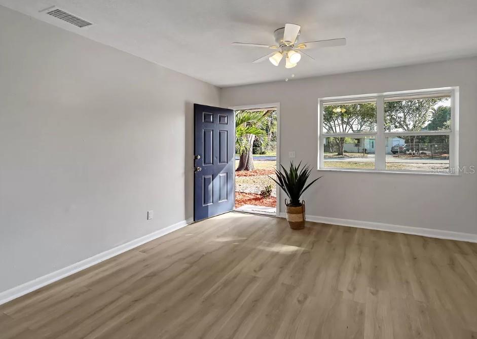 A living room features light wood-look flooring, gray walls, a ceiling fan, and an open door — 4535 38TH COURT, VERO BEACH, FL