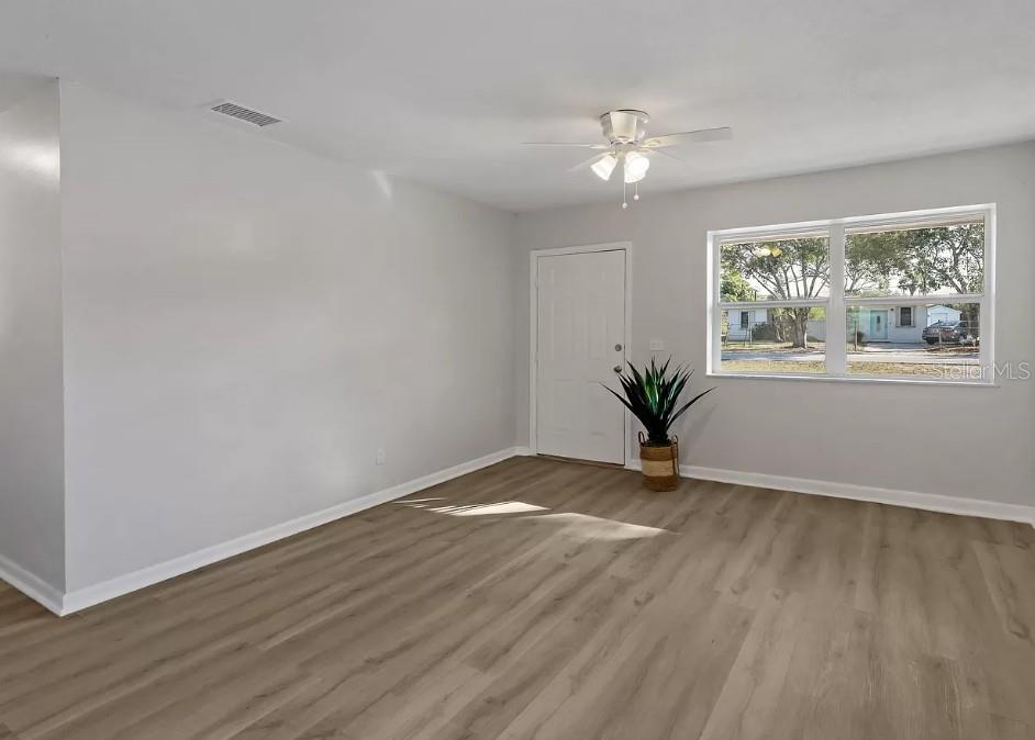 An empty room with light gray walls, wood-look flooring, a ceiling fan, and a window — 4535 38TH COURT, VERO BEACH, FL
