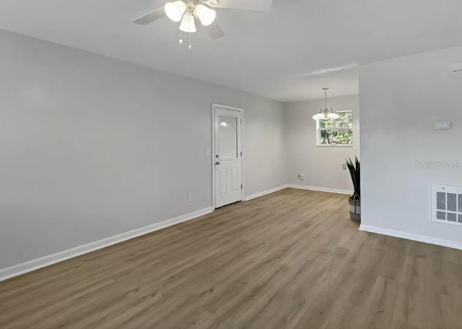 An empty room with light gray walls, wood-look flooring, a ceiling fan, and a door — 4535 38TH COURT, VERO BEACH, FL