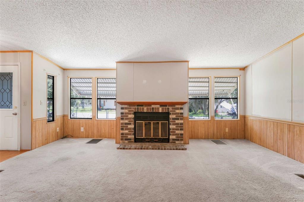 A living room features a brick fireplace, wood paneling, carpeted floors, and multiple windows — 270 S HONEY BEAR WAY, LECANTO, FL