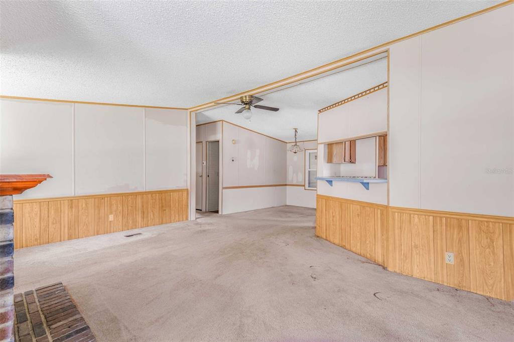 A living room with wood paneling, beige carpet, a brick fireplace, and a ceiling fan — 270 S HONEY BEAR WAY, LECANTO, FL