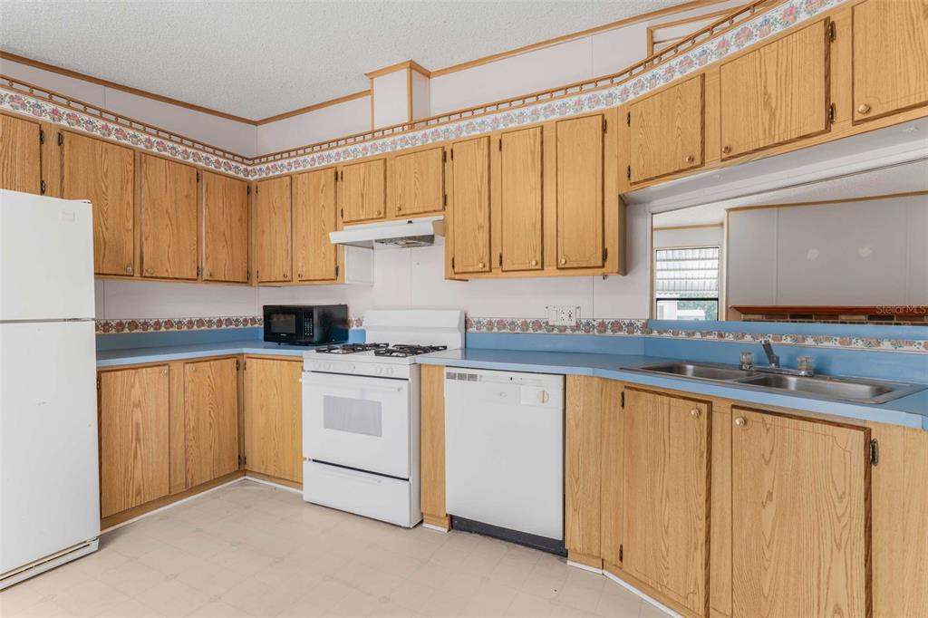 A kitchen features oak cabinets, blue laminate countertops, white appliances, and a floral wallpaper border — 270 S HONEY BEAR WAY, LECANTO, FL
