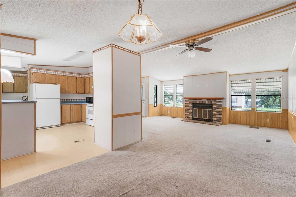 A living room with a brick fireplace and carpeted floors adjacent to a kitchen area — 270 S HONEY BEAR WAY, LECANTO, FL