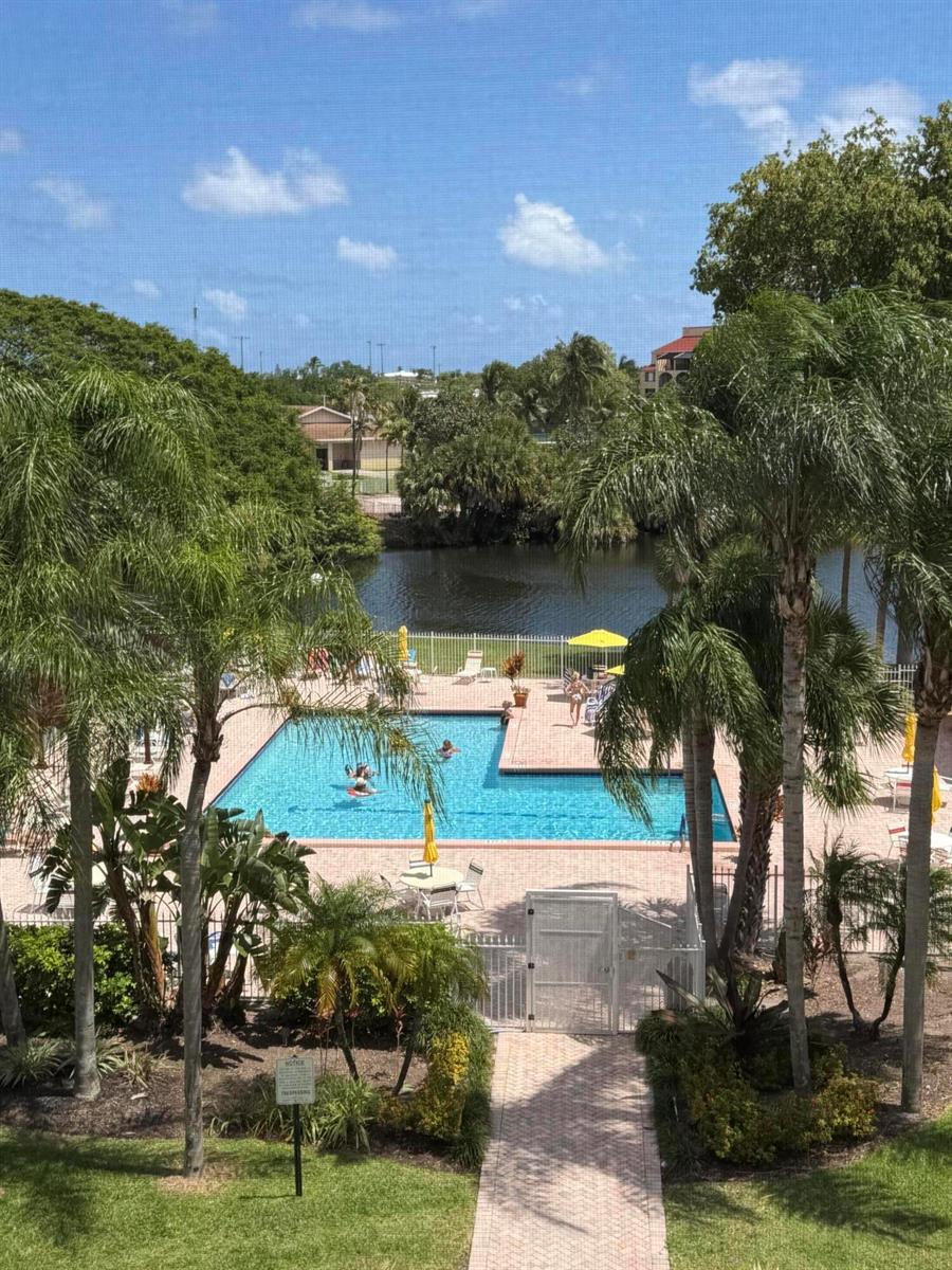 An elevated view of a swimming pool surrounded by palm trees and a small lake — 2255 Lindell Boulevard # 4406, Delray Beach FL 33444, DELRAY BEACH, FL
