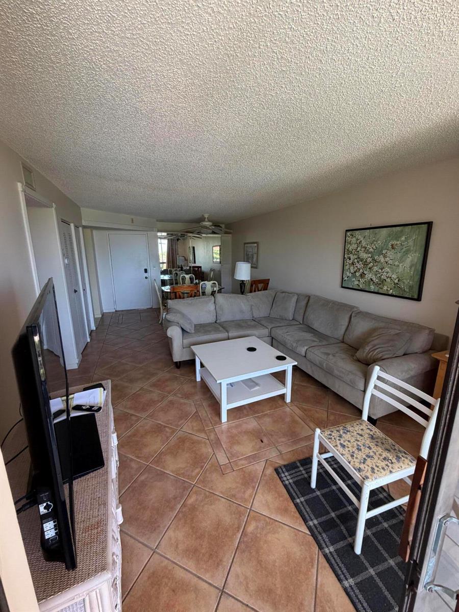 A living room features a beige sectional sofa, a white coffee table, and tile flooring — 2255 Lindell Boulevard # 4406, Delray Beach FL 33444, DELRAY BEACH, FL