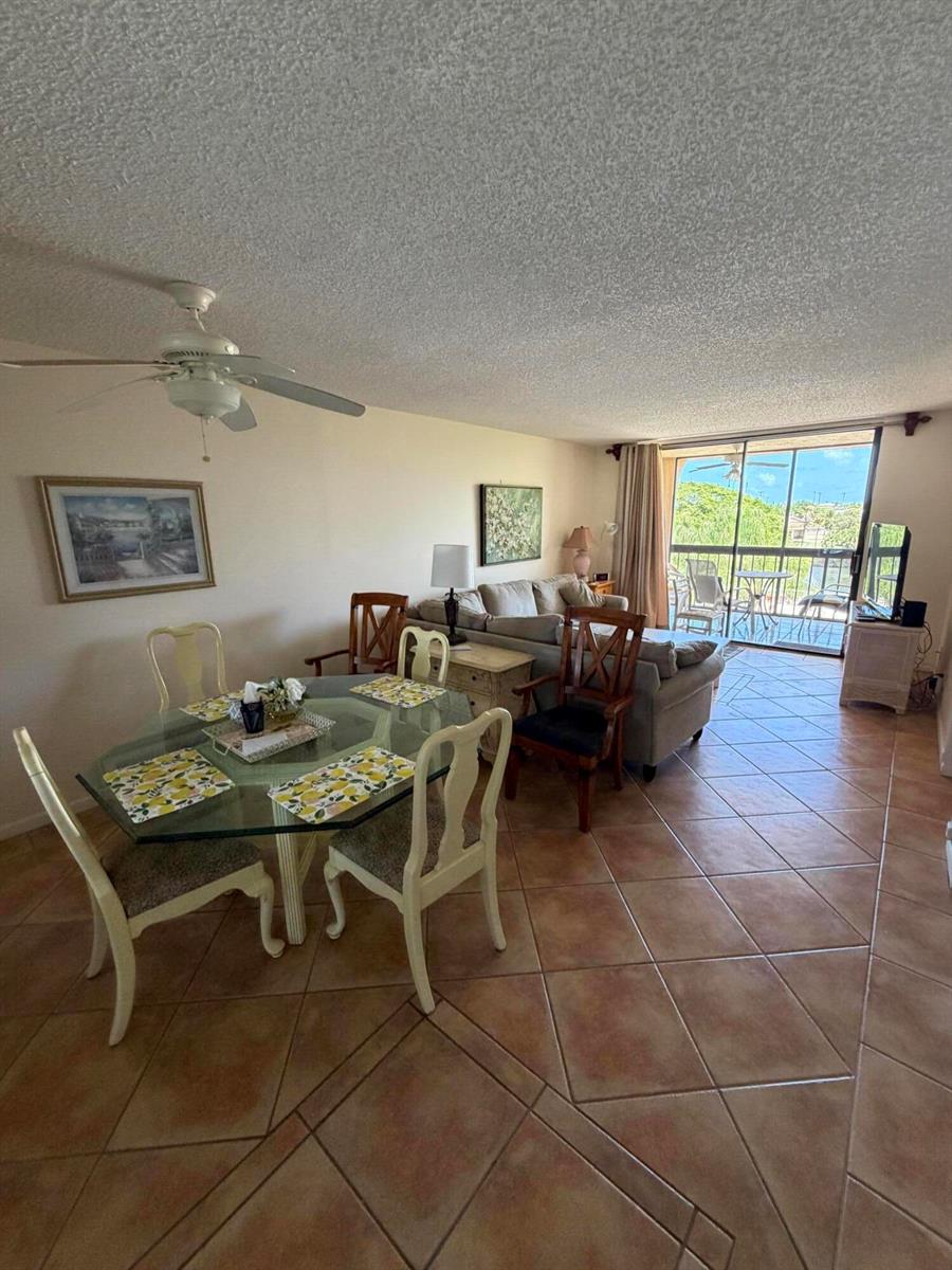 An open-concept living and dining area with tile floors, a glass table, and a balcony — 2255 Lindell Boulevard # 4406, Delray Beach FL 33444, DELRAY BEACH, FL