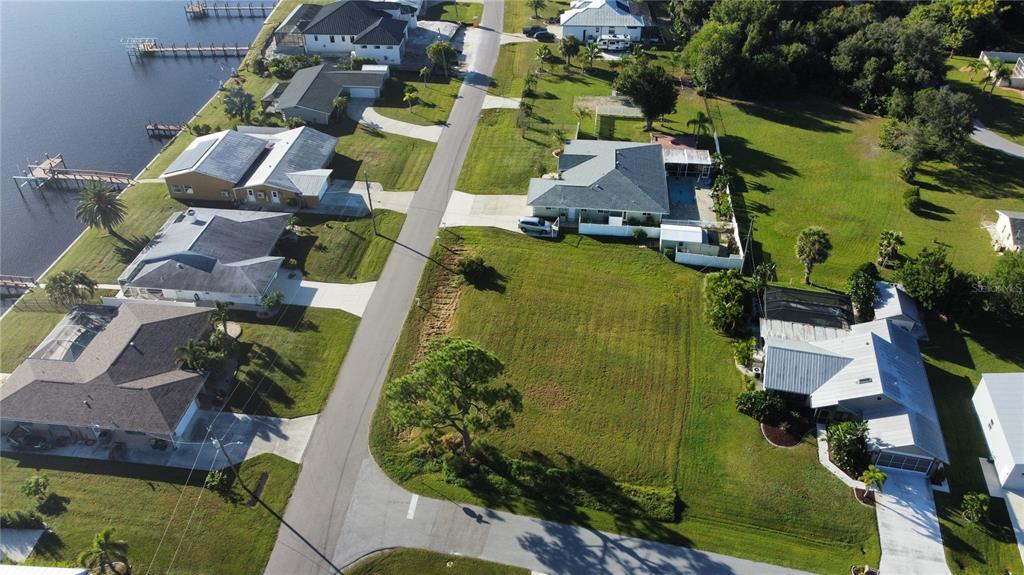 An aerial view shows a vacant residential lot situated between several houses near a waterway — 2297 HARBOUR DRIVE, PUNTA GORDA, FL