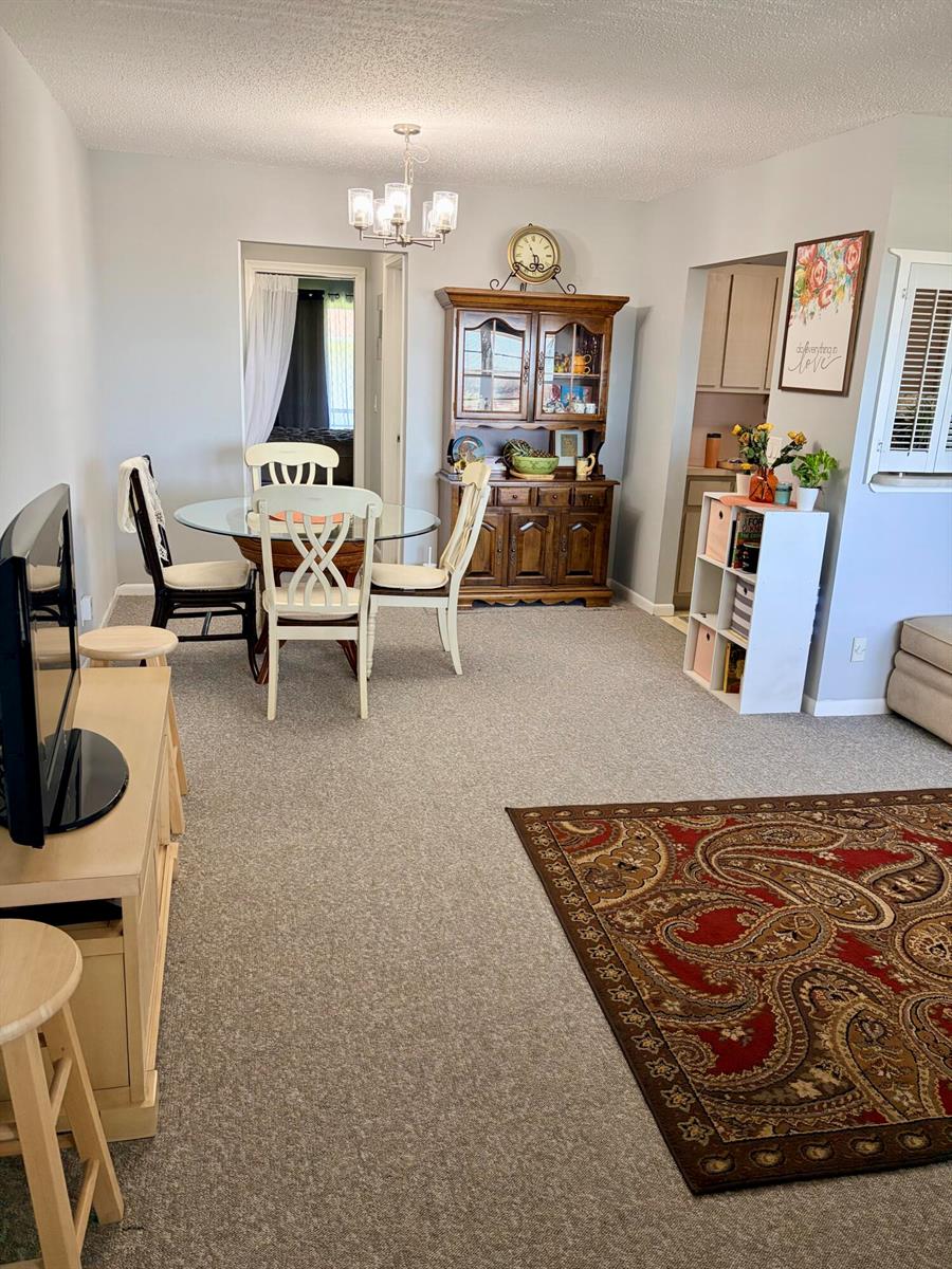 A dining area with a glass table and hutch sits adjacent to a carpeted living room — 14 Easthampton A, West Palm Beach FL 33417, WEST PALM BEACH, FL