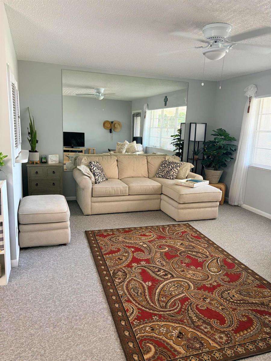 A living room features a beige sectional sofa, a large wall mirror, and a paisley rug — 14 Easthampton A, West Palm Beach FL 33417, WEST PALM BEACH, FL