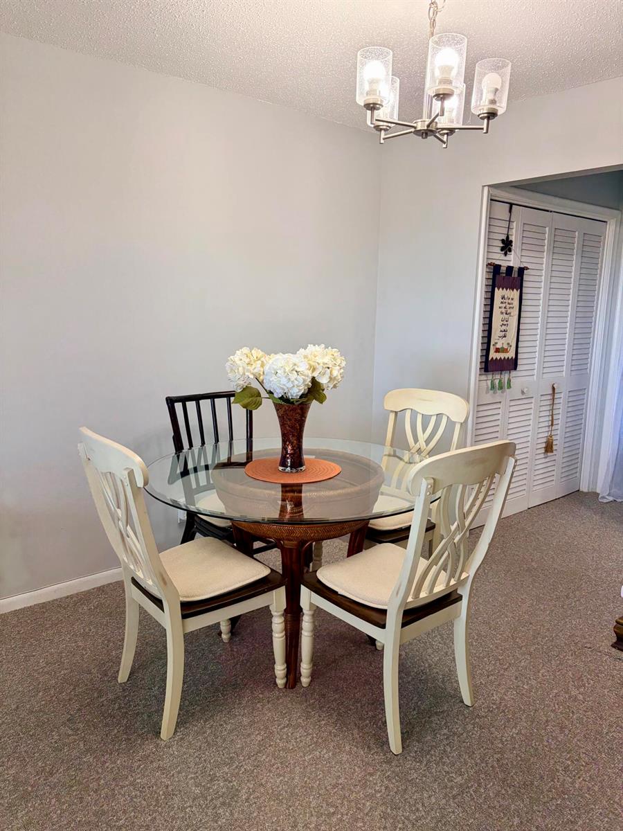 A dining area features a round glass-topped table with four chairs and a light fixture — 14 Easthampton A, West Palm Beach FL 33417, WEST PALM BEACH, FL
