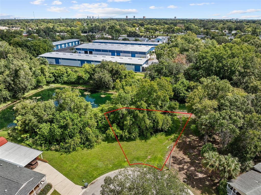 An aerial view shows a vacant, trapezoidal lot outlined in red next to a pond — 1082 YAUPON STREET, DAYTONA BEACH, FL