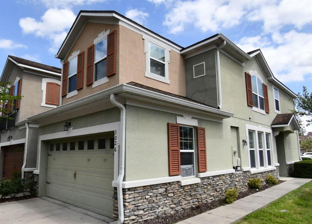 A two-story house exterior features a garage, stone veneer, stucco walls, and brown window shutters — 3026 VICTORIA GLEN DRIVE, SANFORD, FL