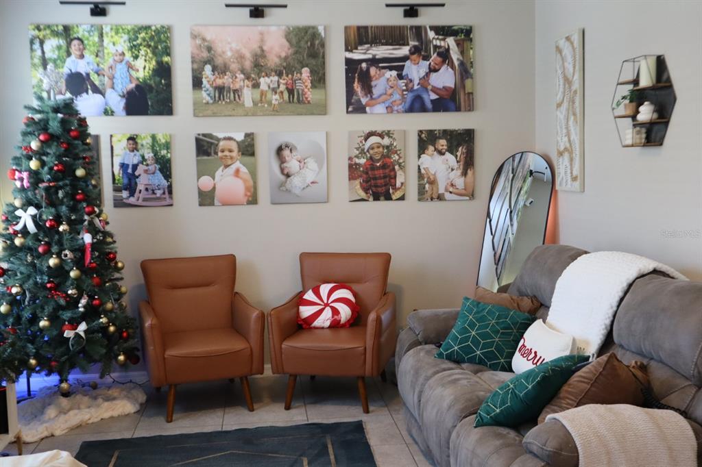 A living room features a Christmas tree, two leather chairs, a sofa, and wall-mounted photos — 3026 VICTORIA GLEN DRIVE, SANFORD, FL