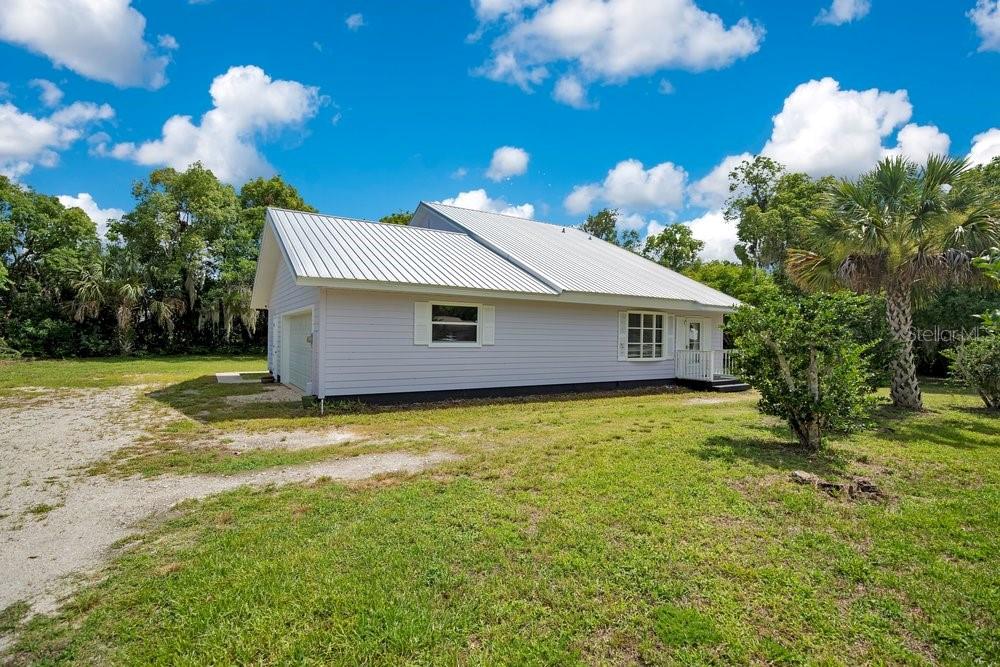 A light-colored single-story house with a metal roof sits on a grassy lot — 110 W WASHINGTON AVENUE, DELAND, FL