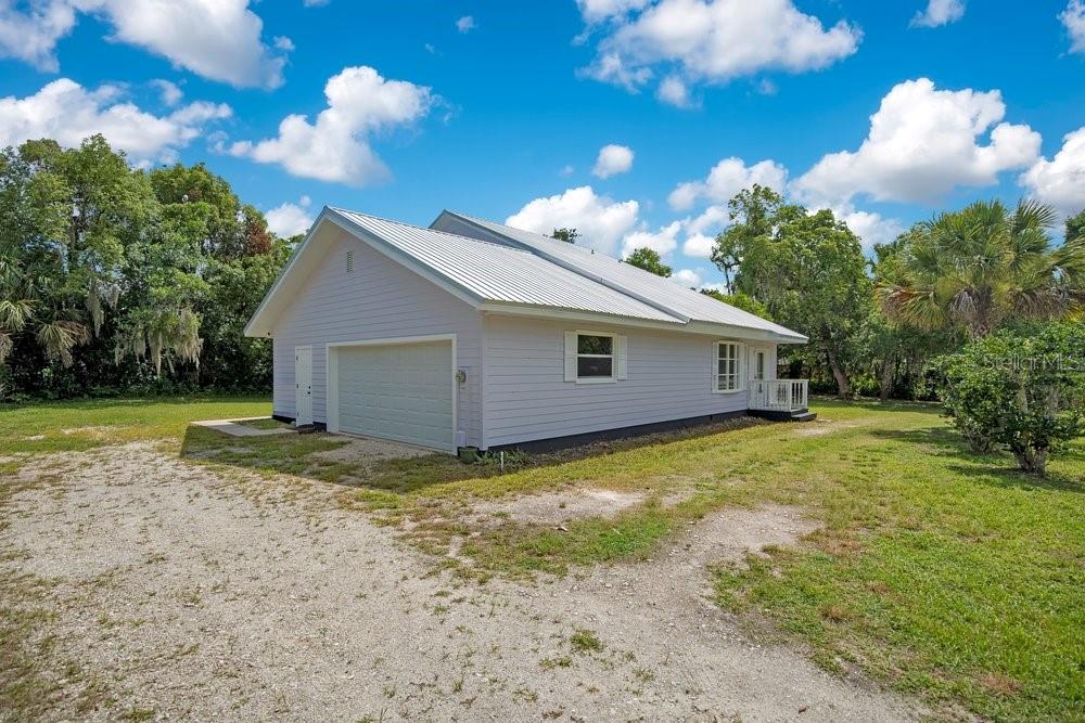 A light-colored house with a metal roof and an attached garage sits on a lot — 110 W WASHINGTON AVENUE, DELAND, FL