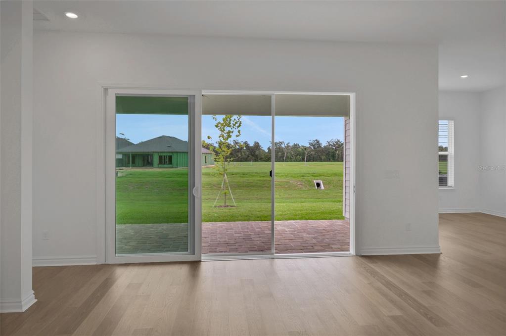 A room with light wood flooring features a large sliding glass door opening to a patio — 48 RIBERA DRIVE, FLAGLER BEACH, FL