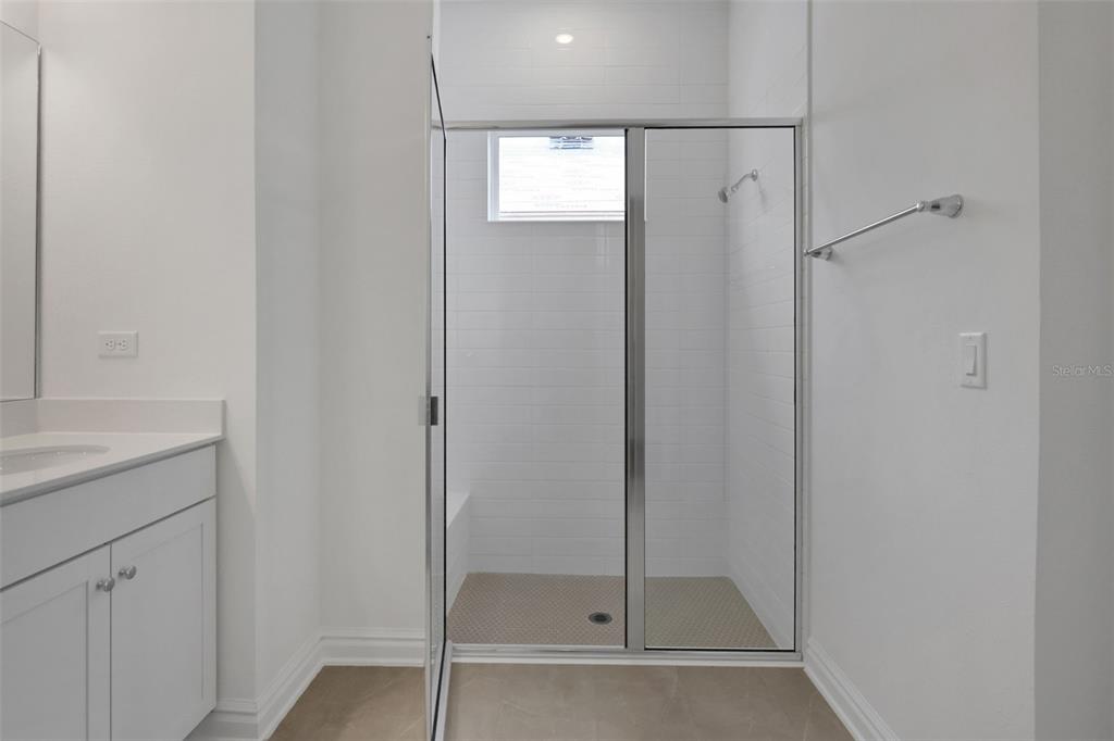 A bathroom features a white vanity, a tiled walk-in shower with a glass door, and tile flooring — 48 RIBERA DRIVE, FLAGLER BEACH, FL
