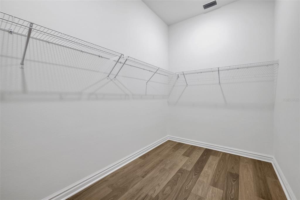 A walk-in closet with white walls, wire shelving, and wood-look flooring — 48 RIBERA DRIVE, FLAGLER BEACH, FL