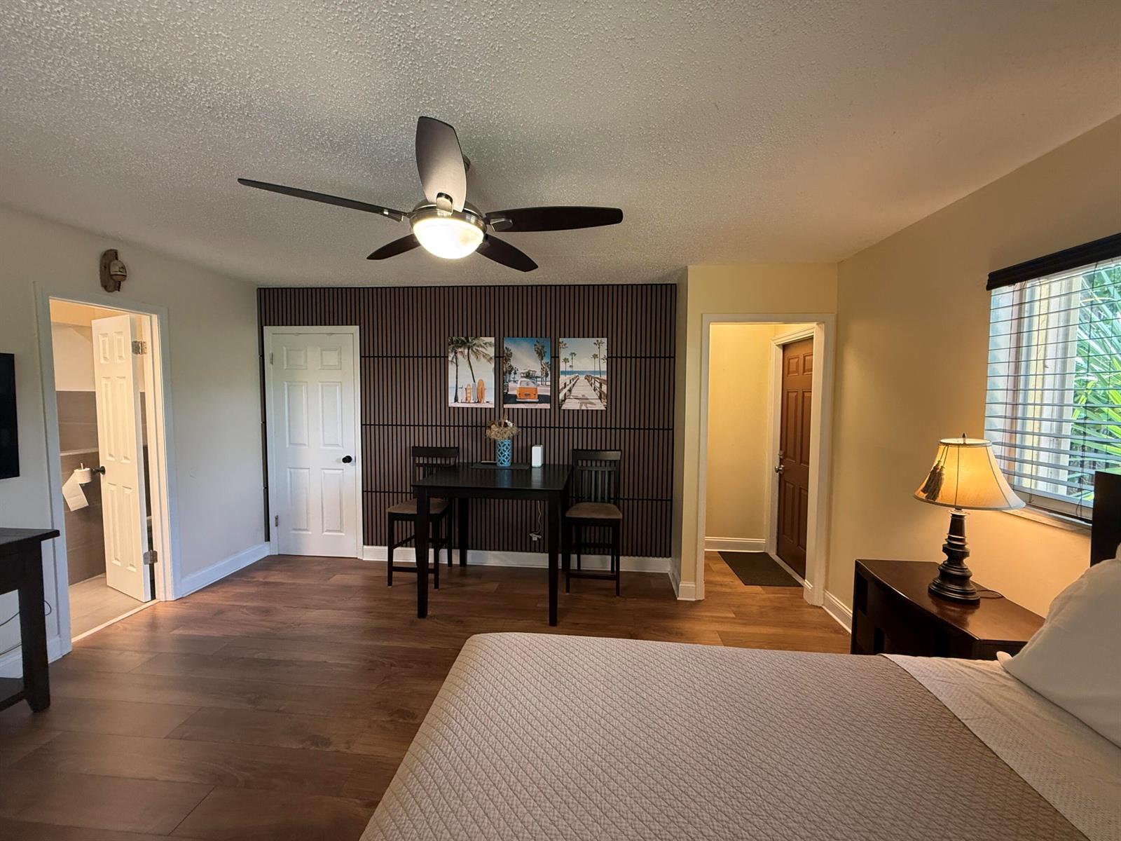 A bedroom features a wood-slat accent wall, a dining set, and a ceiling fan — 803 NE 2nd Avenue, Delray Beach FL 33444, DELRAY BEACH, FL