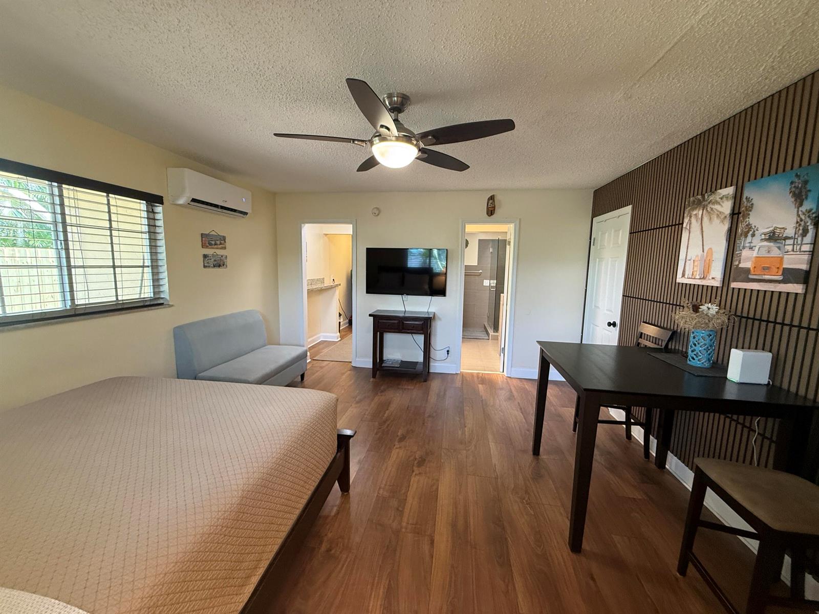 A bedroom features a bed, a small sofa, a dining table, and wood-look flooring — 803 NE 2nd Avenue, Delray Beach FL 33444, DELRAY BEACH, FL