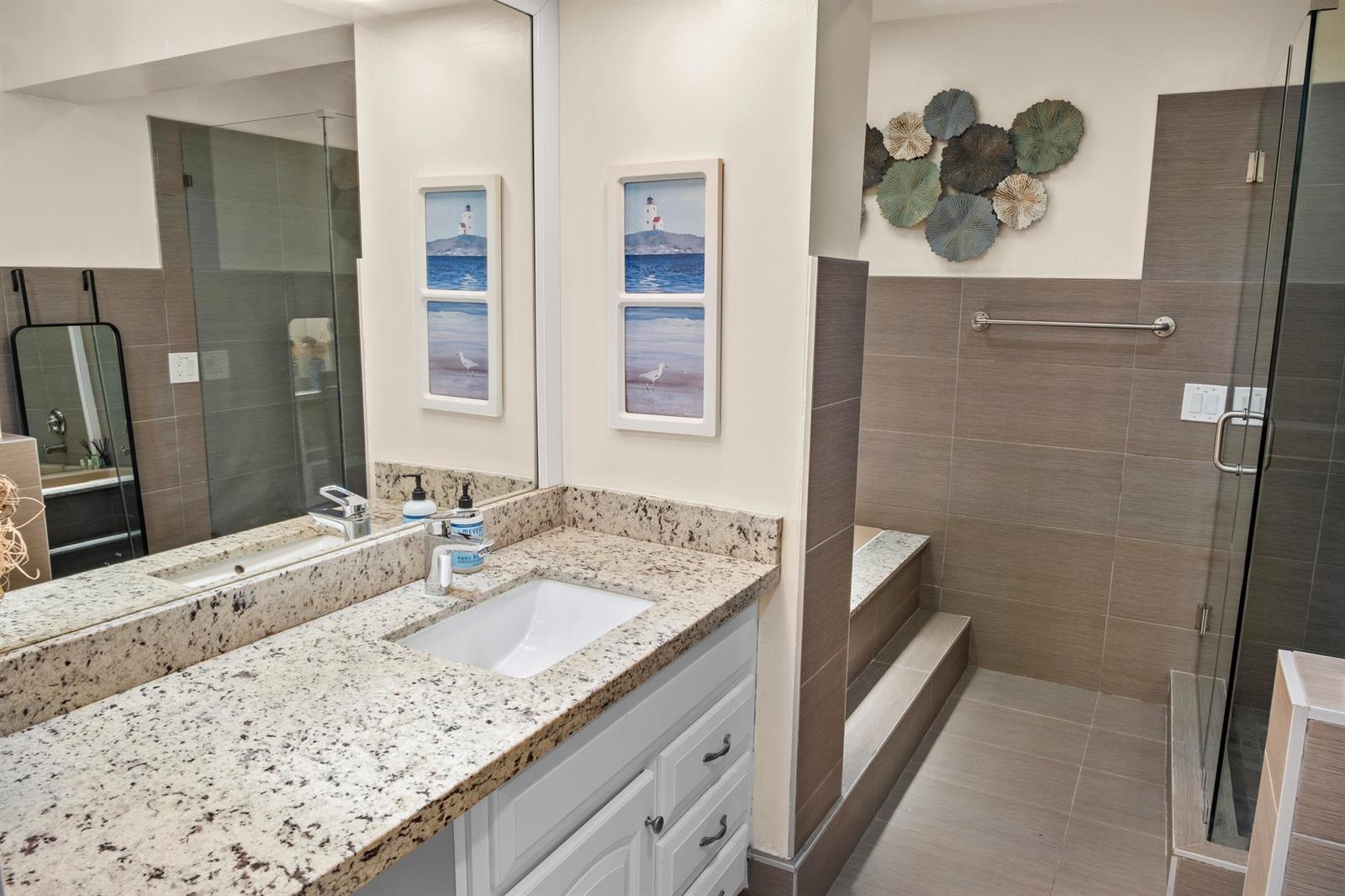 A bathroom features a granite vanity, white cabinets, a walk-in shower, and wall-mounted decor — 803 NE 2nd Avenue, Delray Beach FL 33444, DELRAY BEACH, FL