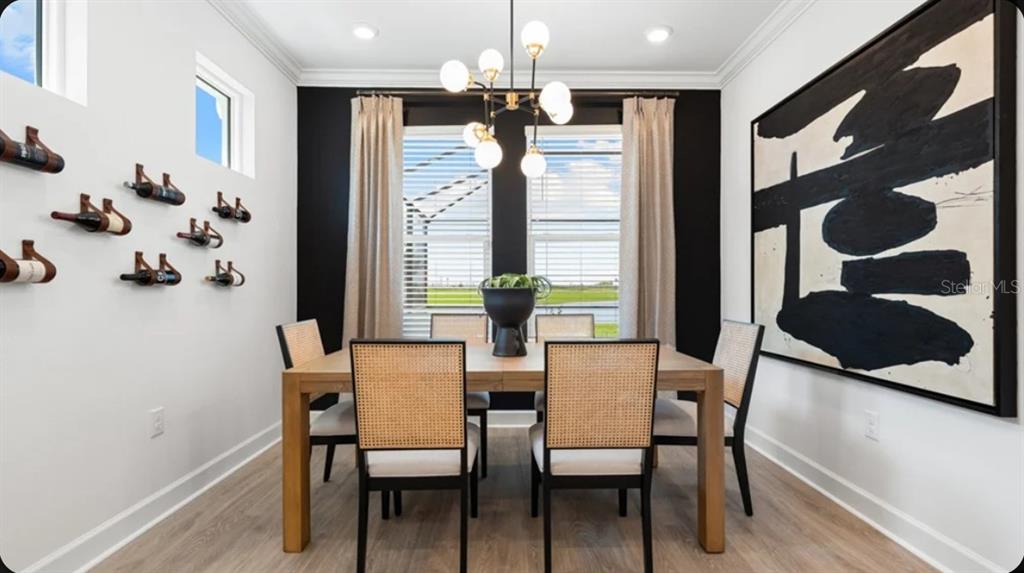 A dining room features a wooden table, cane-back chairs, wall-mounted wine racks, and abstract art — 7416 MOONBEAM AVENUE, SARASOTA, FL