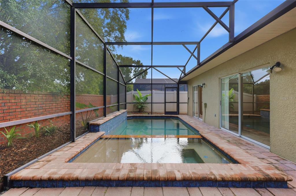 A screened-in patio features a rectangular swimming pool with a raised tiled spa — 13714 HUNTWICK DRIVE, ORLANDO, FL