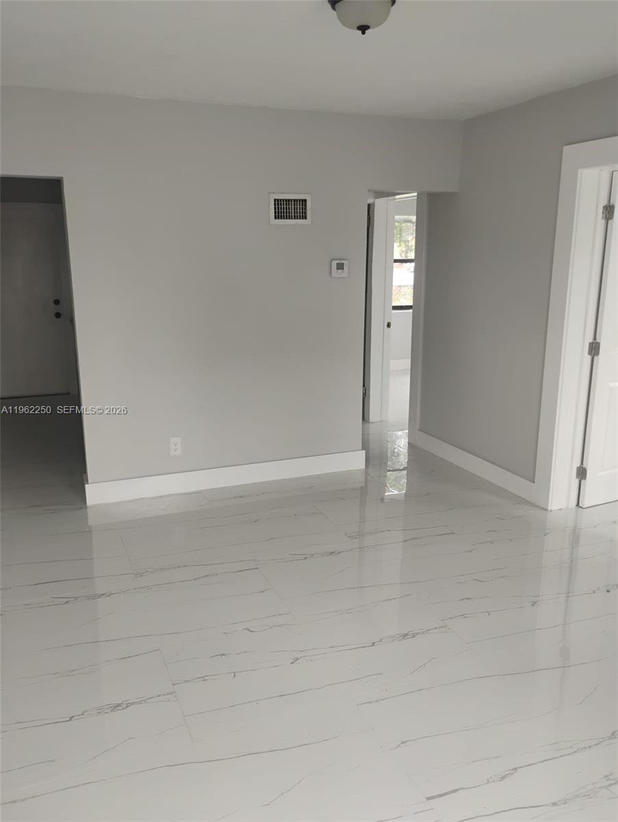 An interior room features light gray walls, white trim, and glossy white marble-look tile flooring — 908 SW Avenue D, Belle Glade FL 33430, BELLE GLADE, FL