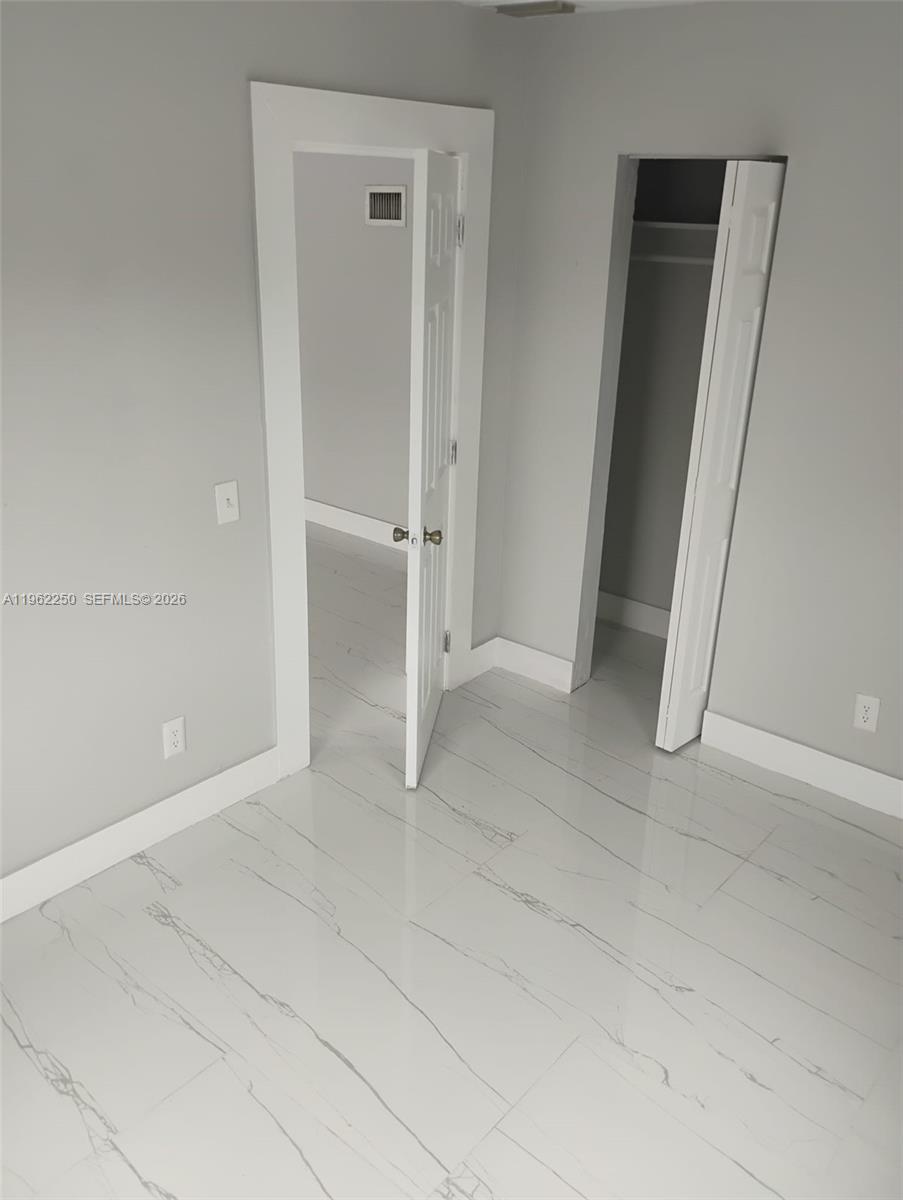 A room with white marble-style tile flooring, two doorways, and light gray walls — 908 SW Avenue D, Belle Glade FL 33430, BELLE GLADE, FL