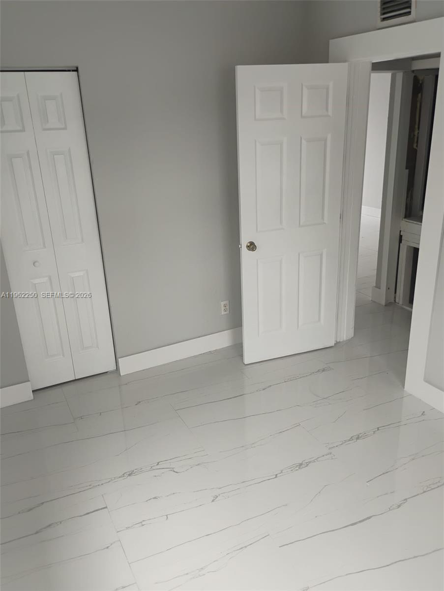 A room with white tile flooring, gray walls, and two white interior doors — 908 SW Avenue D, Belle Glade FL 33430, BELLE GLADE, FL