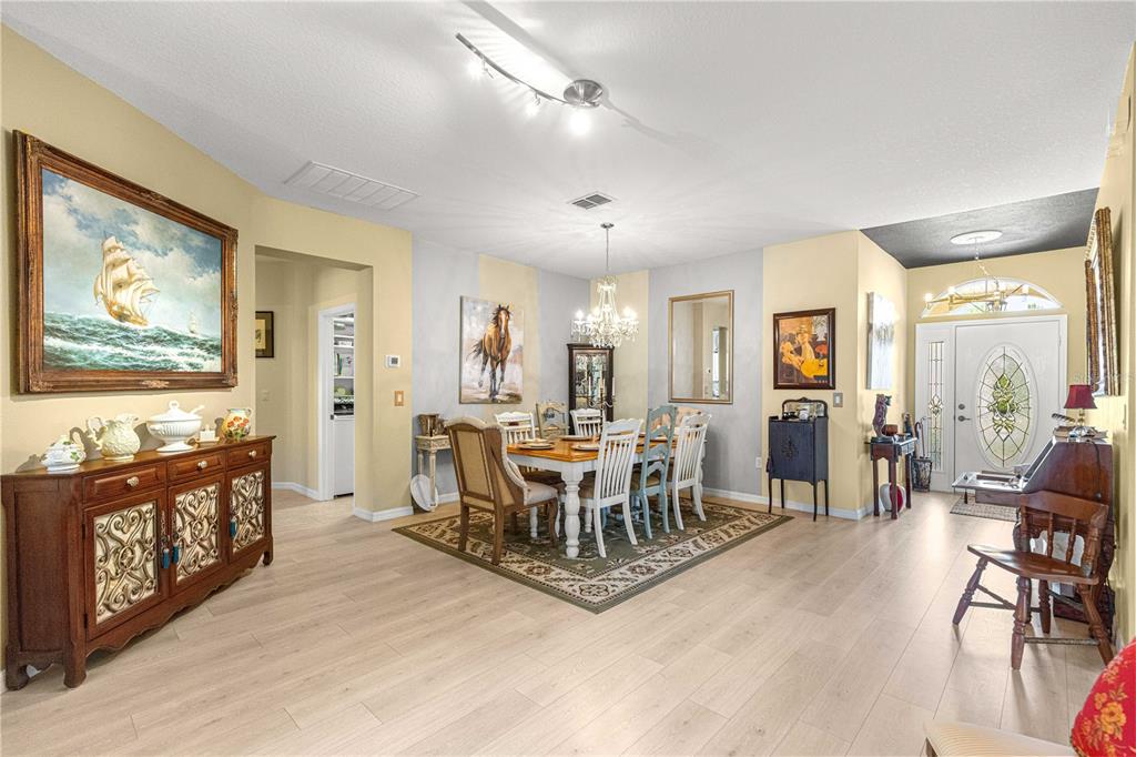 A dining room with light wood floors, a chandelier, and a large ship painting — 9359 SW 94TH LOOP, OCALA, FL