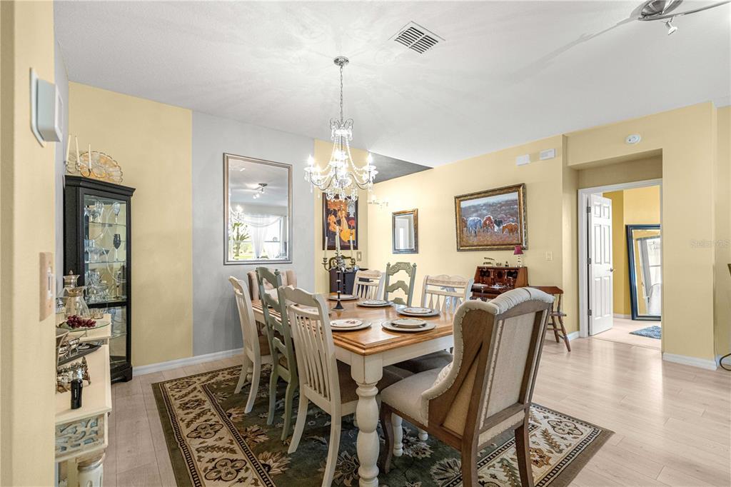 A dining room features a wooden table, upholstered chairs, a chandelier, and a display cabinet — 9359 SW 94TH LOOP, OCALA, FL