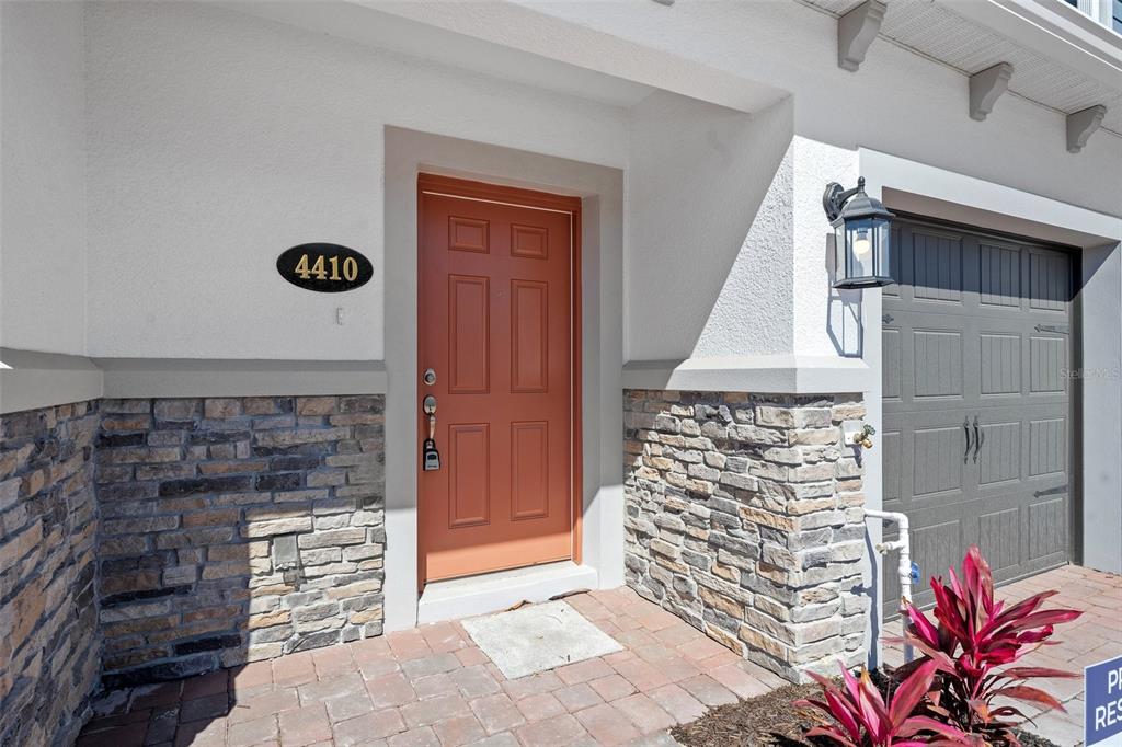 The exterior entrance features a red door, stone veneer siding, and a gray garage door — 4410 CAMPSITE LOOP, ORLANDO, FL