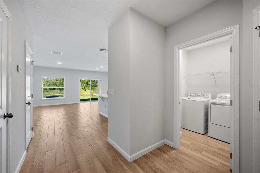 A laundry room with a washer and dryer opens into a bright, open-concept living area — 4410 CAMPSITE LOOP, ORLANDO, FL