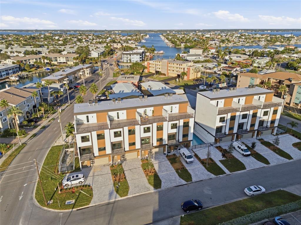 An aerial view of modern townhomes with attached garages and balconies near a waterfront community — 11605 1ST STREET E UNIT A2, TREASURE ISLAND, FL