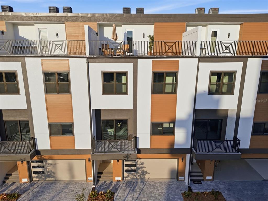 An exterior view of a multi-story townhouse complex featuring balconies, garages, and modern siding — 11605 1ST STREET E UNIT A2, TREASURE ISLAND, FL