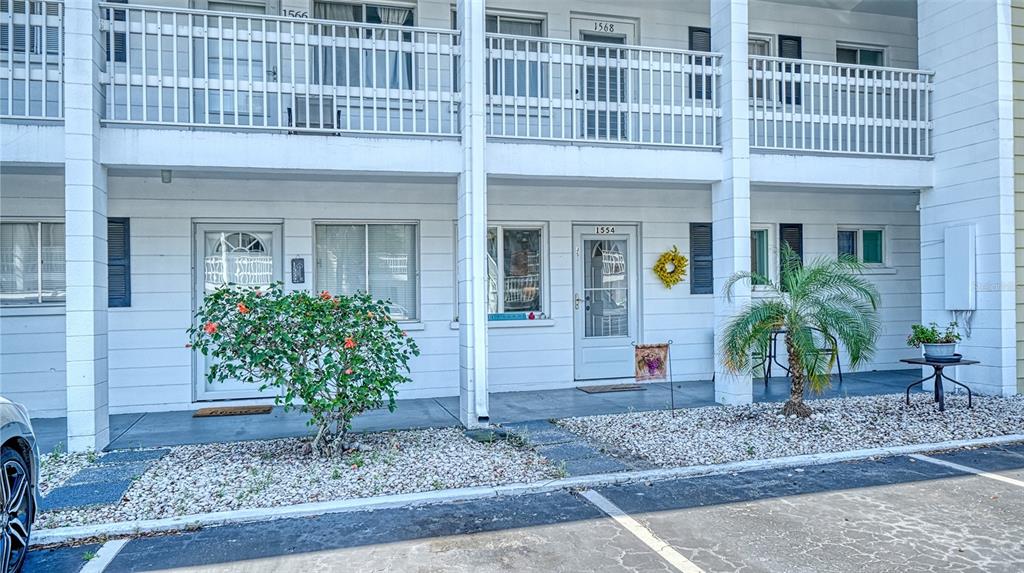 The exterior of a two-story apartment building features white siding, balconies, and ground-level entryways — 1554 PLEASANT ROAD UNIT J5, BRADENTON, FL