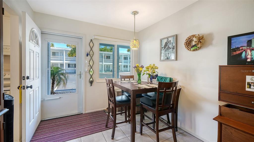 A dining area features a wooden table with four chairs, tile flooring, and a glass door — 1554 PLEASANT ROAD UNIT J5, BRADENTON, FL