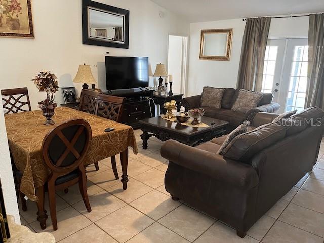 A living room and dining area feature tile flooring, a dark sofa, and a television — 3723 IMPERIAL DRIVE, WINTER HAVEN, FL