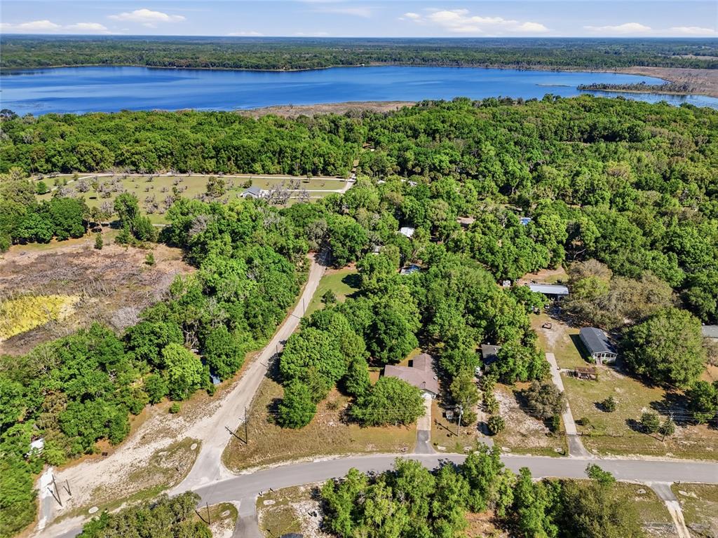 An aerial view shows a residential area with houses surrounded by trees near a lake — 347 ASHLEY STREET, HAWTHORNE, FL